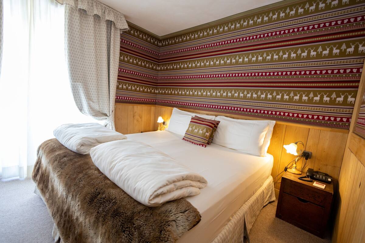 Un dormitorio con una cama grande, cabecera de madera y mesita de noche con lámpara y teléfono.