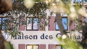 Un edificio con el letrero "Maison des Cisa" y varias ventanas con persianas.