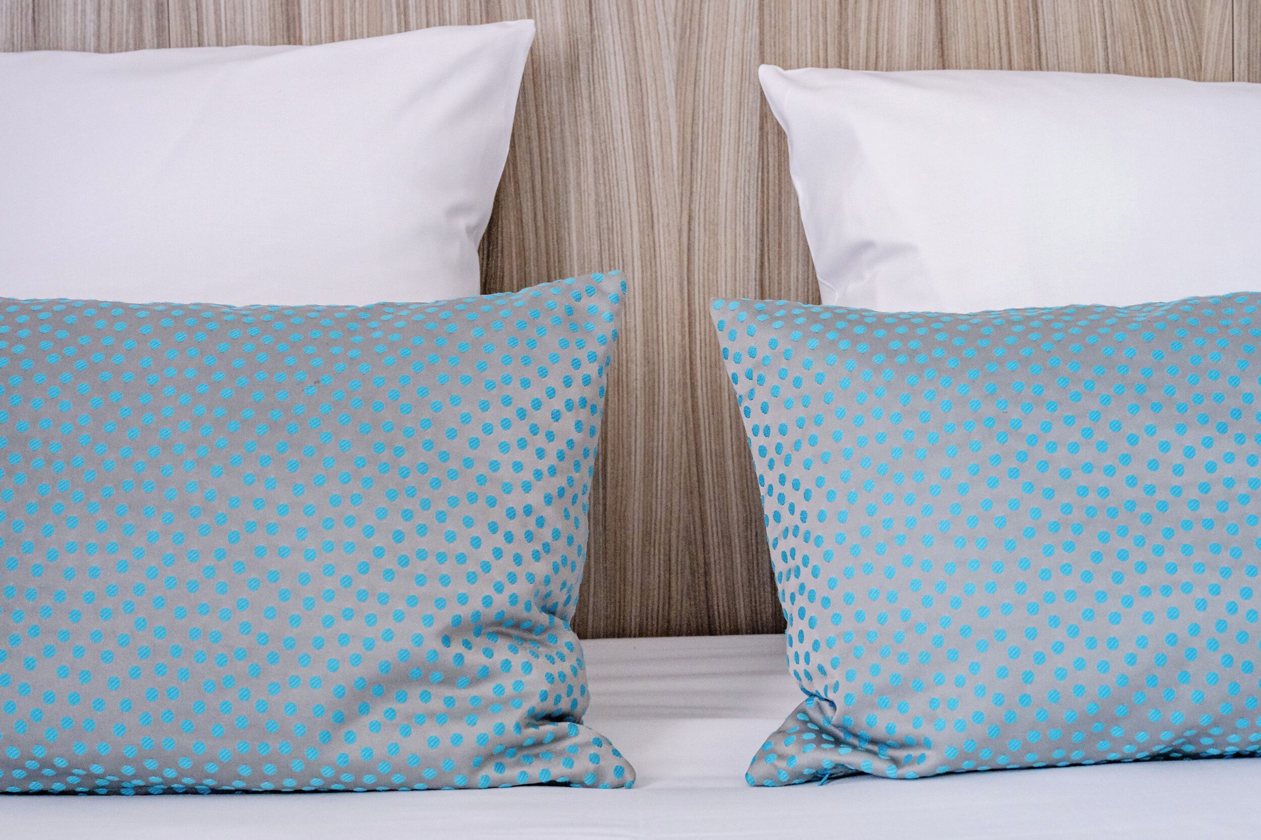 Een bed met twee kussens, één wit en één blauw met stippen.