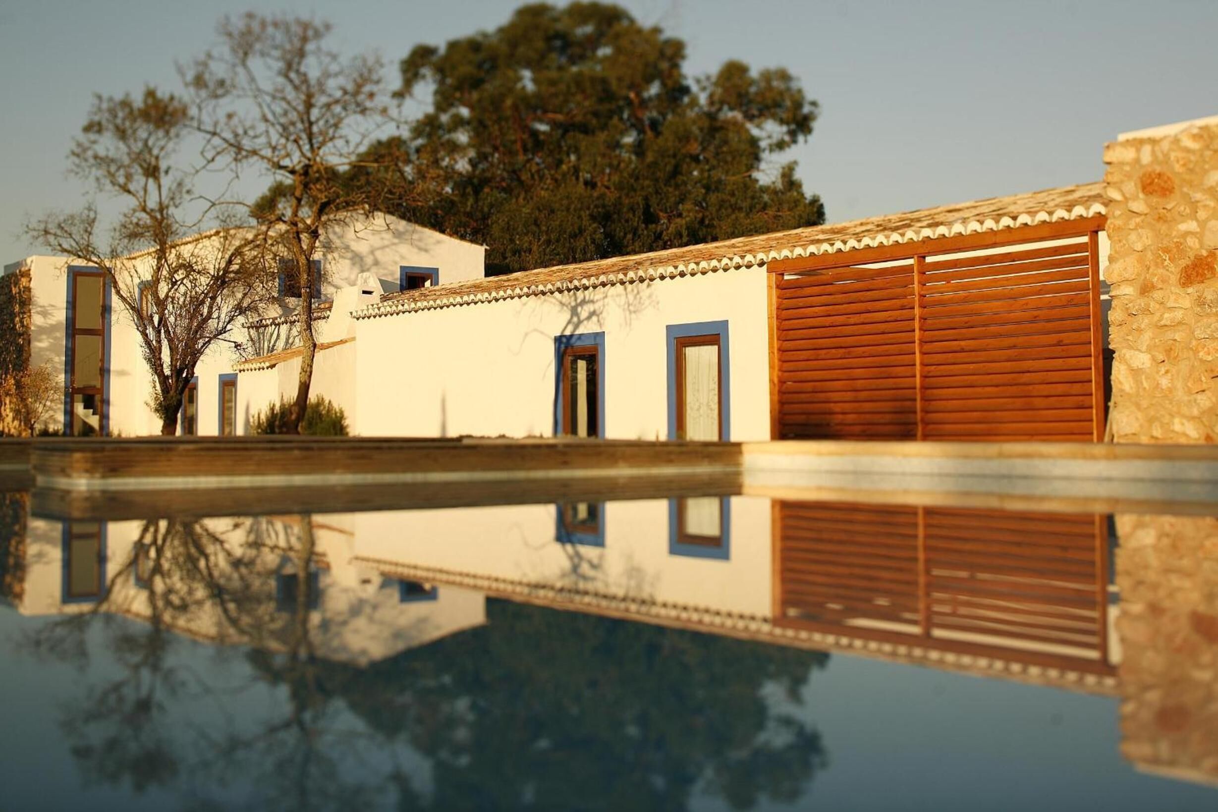 A building with a reflective pool, a wooden door, and a stone wall.