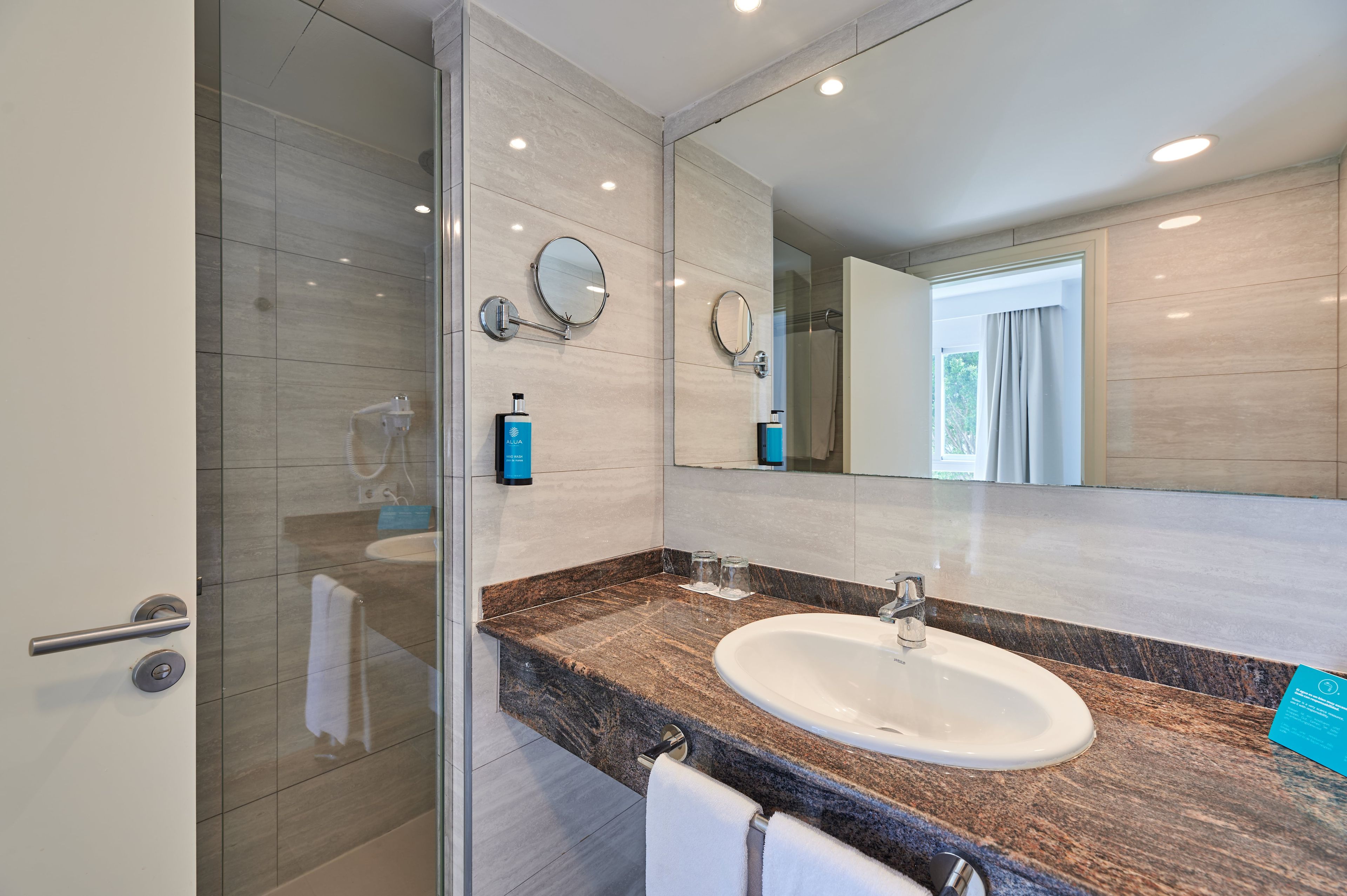 Une salle de bain moderne avec une douche à parois de verre, un comptoir en marbre et un grand miroir.