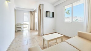 A modern living room with a sofa, a coffee table, and a TV mounted on the wall. - Aluasun Continental Park Hotel & Apartments (Muro)