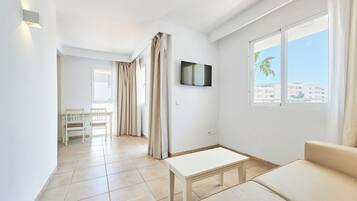Ein modernes Wohnzimmer mit einer Couch, einem Couchtisch und einem an der Wand befestigten Fernseher.