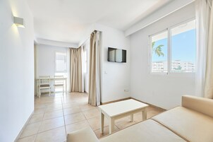 Una sala de estar moderna con un sofá, una mesa de centro y un televisor montado en la pared.