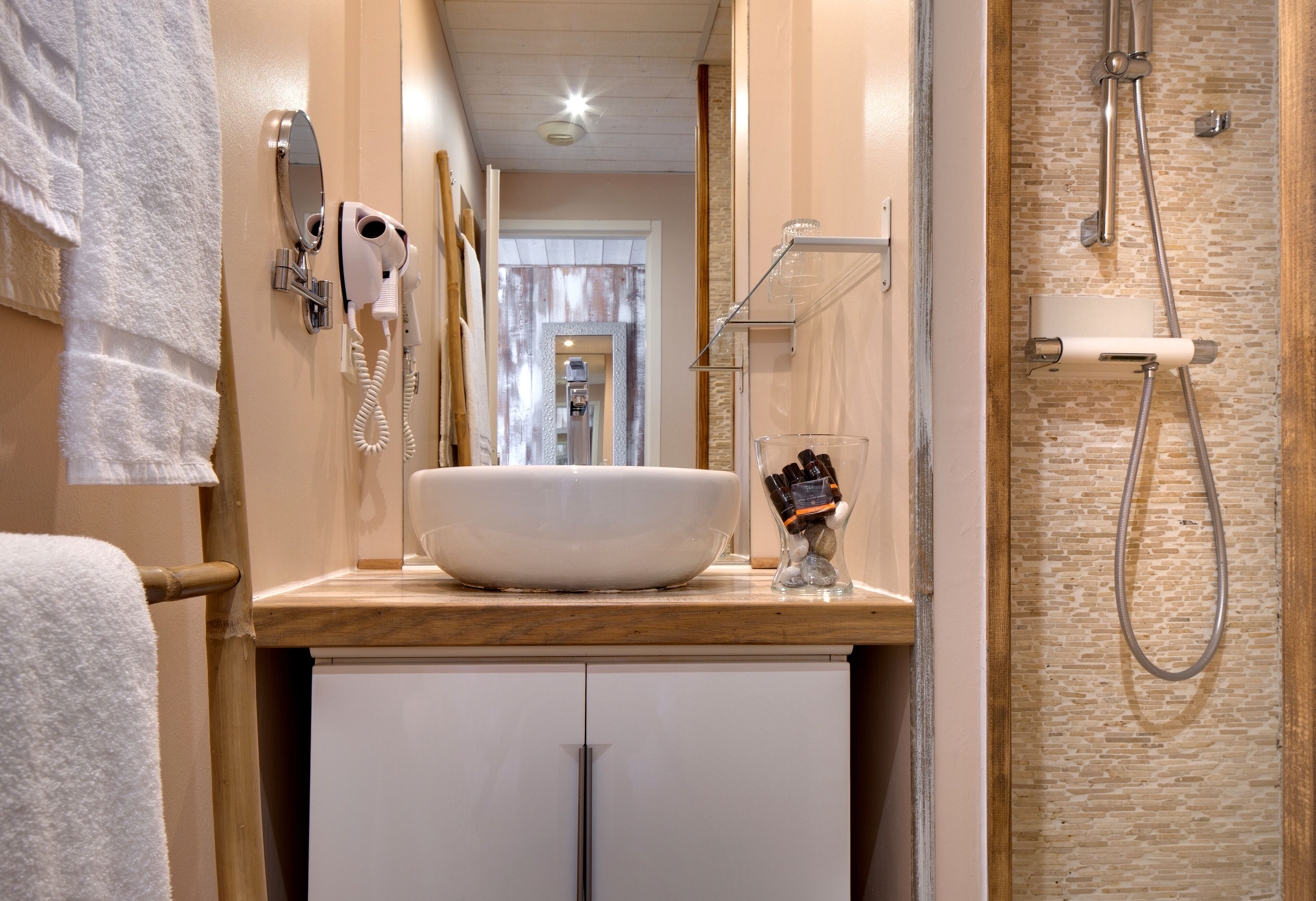 Ein Badezimmer mit einem großen, weißen Waschbecken, einem Handtrockner, einem Handtuchhalter und einer Dusche mit Glaswand.