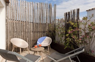 Un patio con dos sillones de descanso, una mesita redonda y una bebida.