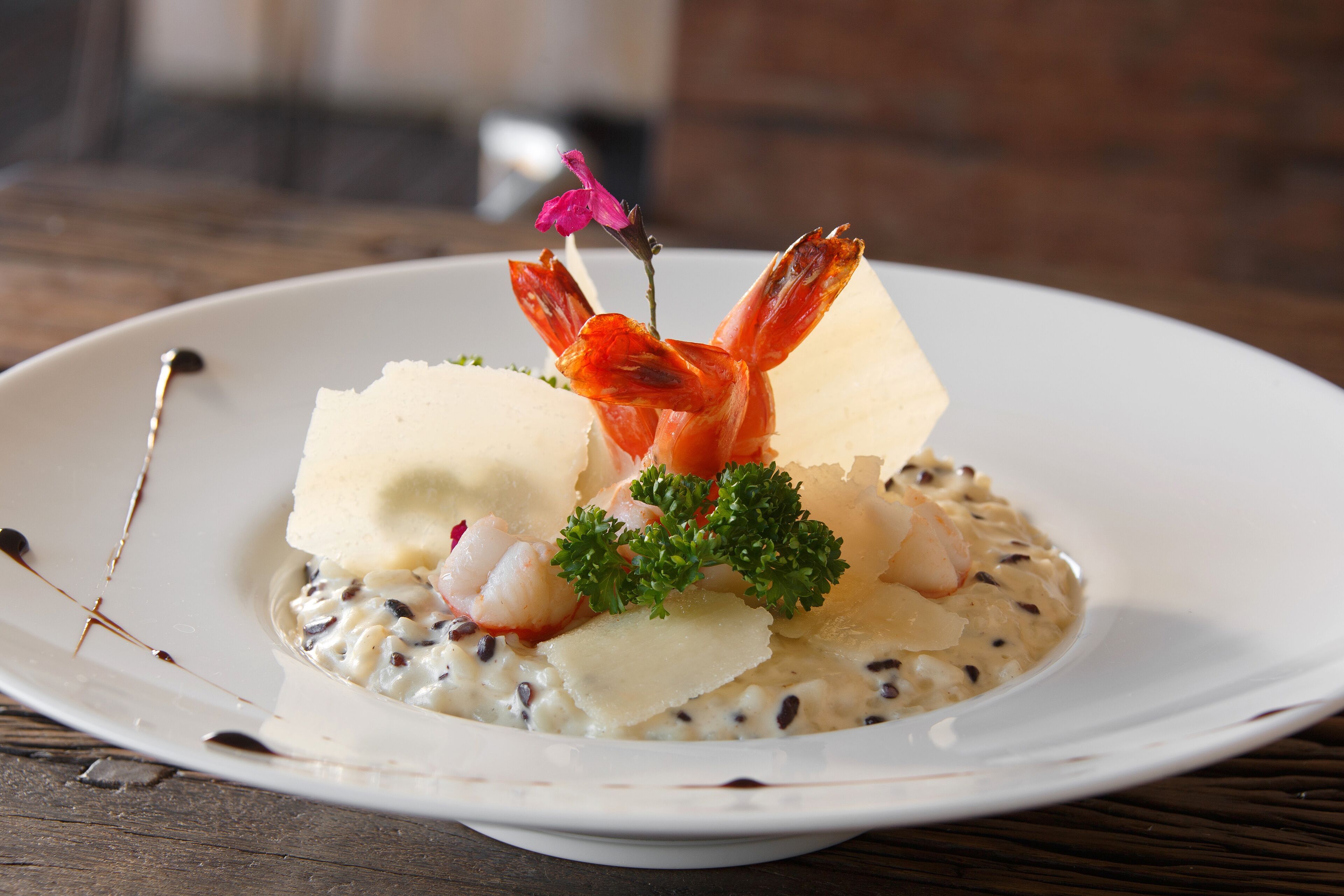 A plate of seafood risotto with shrimp, squid, and a garnish of parsley.