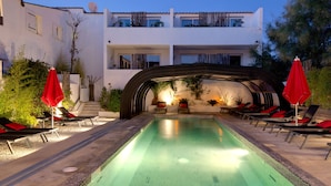A swimming pool with lounge chairs and umbrellas, surrounded by a white building with balconies. - Vila de la Mar & Spa (Saintes-Maries-de-la-Mer)