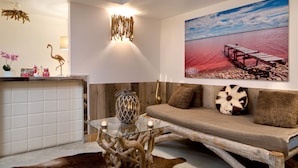 A modern living room with a glass coffee table, wooden sofa, and a painting of a pier. - Vila de la Mar & Spa (Saintes-Maries-de-la-Mer)
