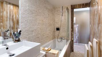 Un baño moderno con pared de piedra, una bañera y una ducha.