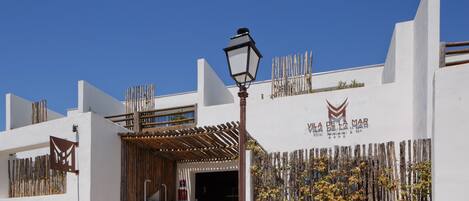 A building with a white facade, a wooden fence, and a sign that reads "Vila de la Mar".