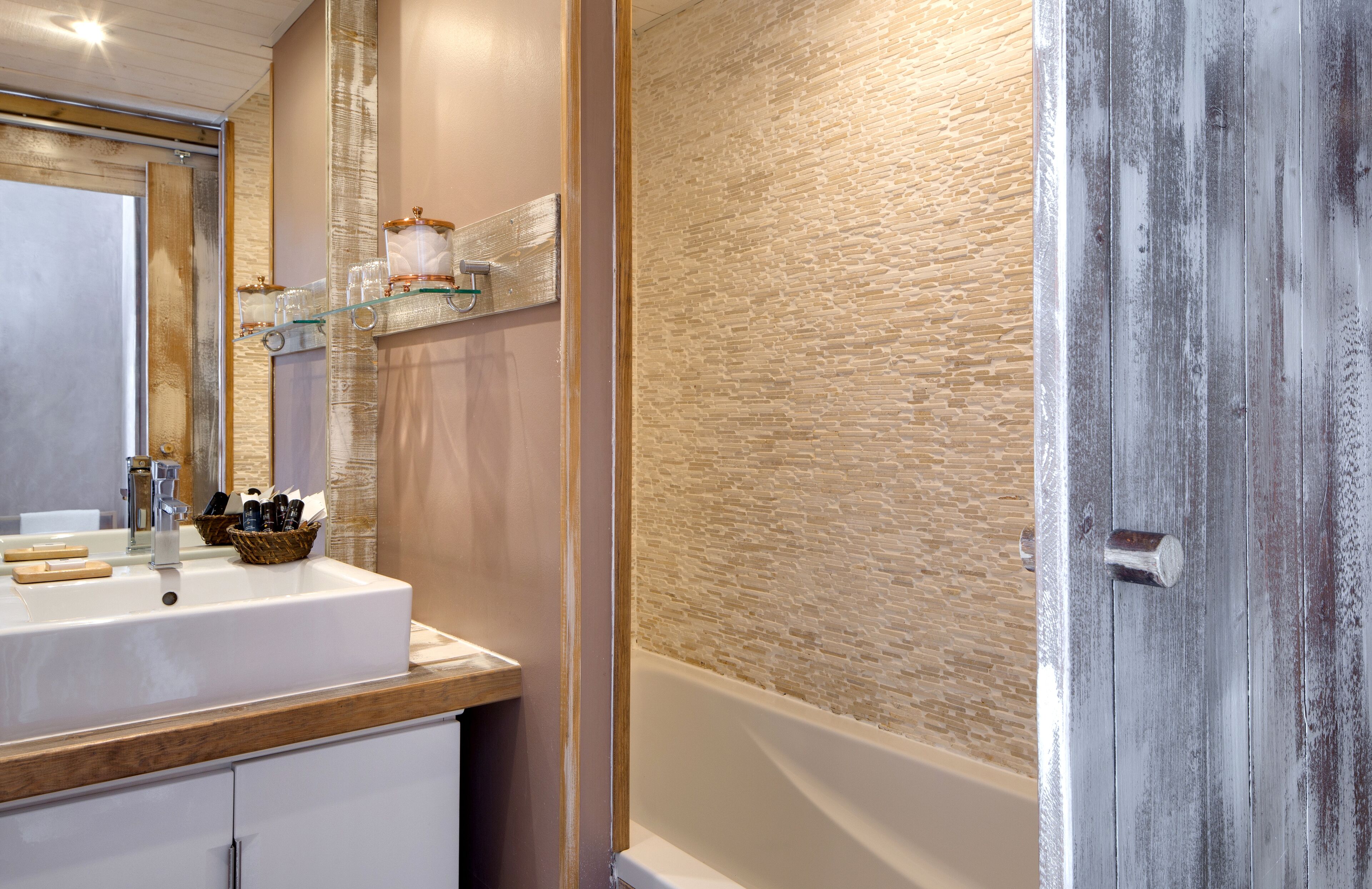 A bathroom with a white sink, a mirror, and a wooden door.