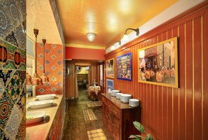 A hallway with patterned tiles, a wooden counter with plates, and a mural on the wall. - Hotel Salvator (Prague)