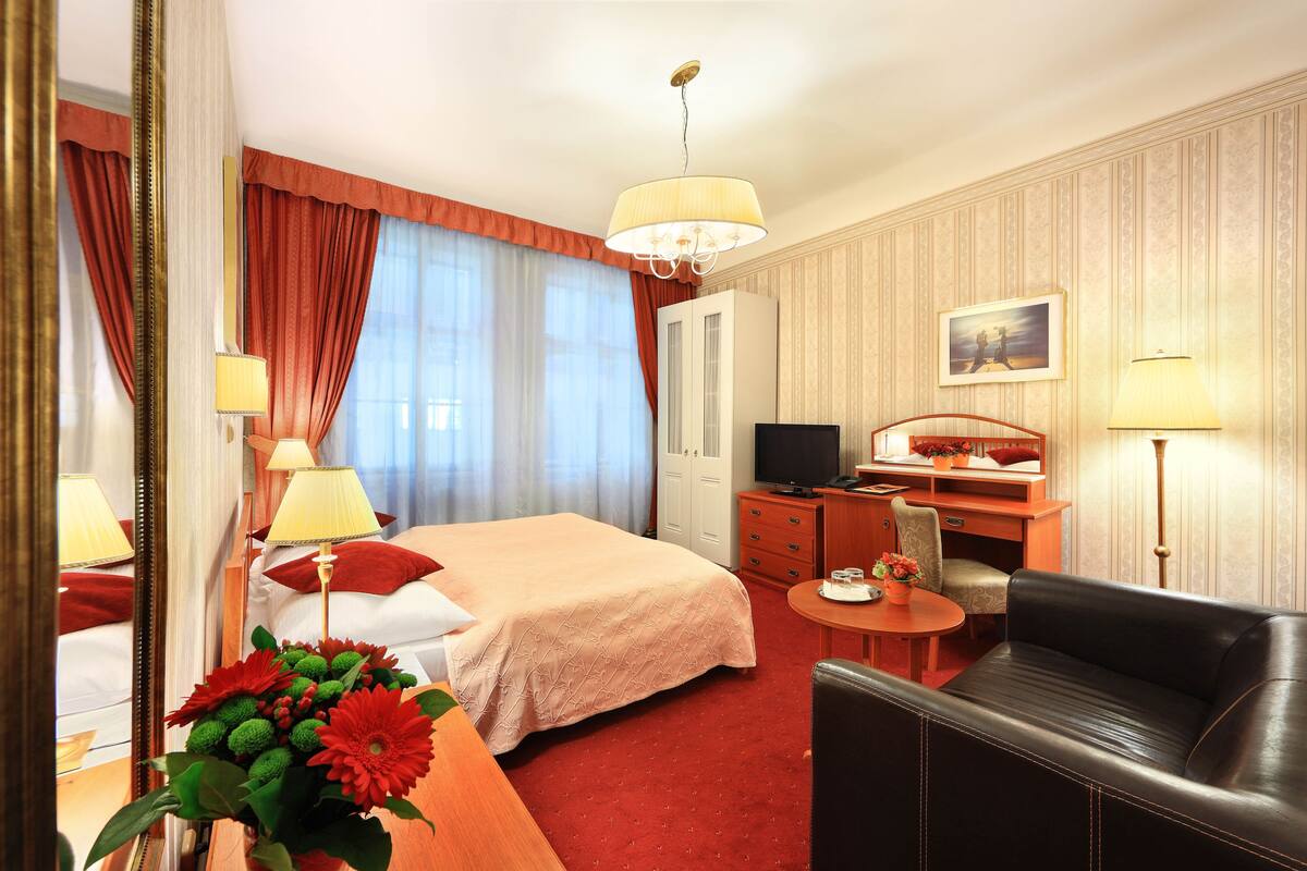 Een hotelkamer met een bed, bureau, stoel, televisie en een bank.