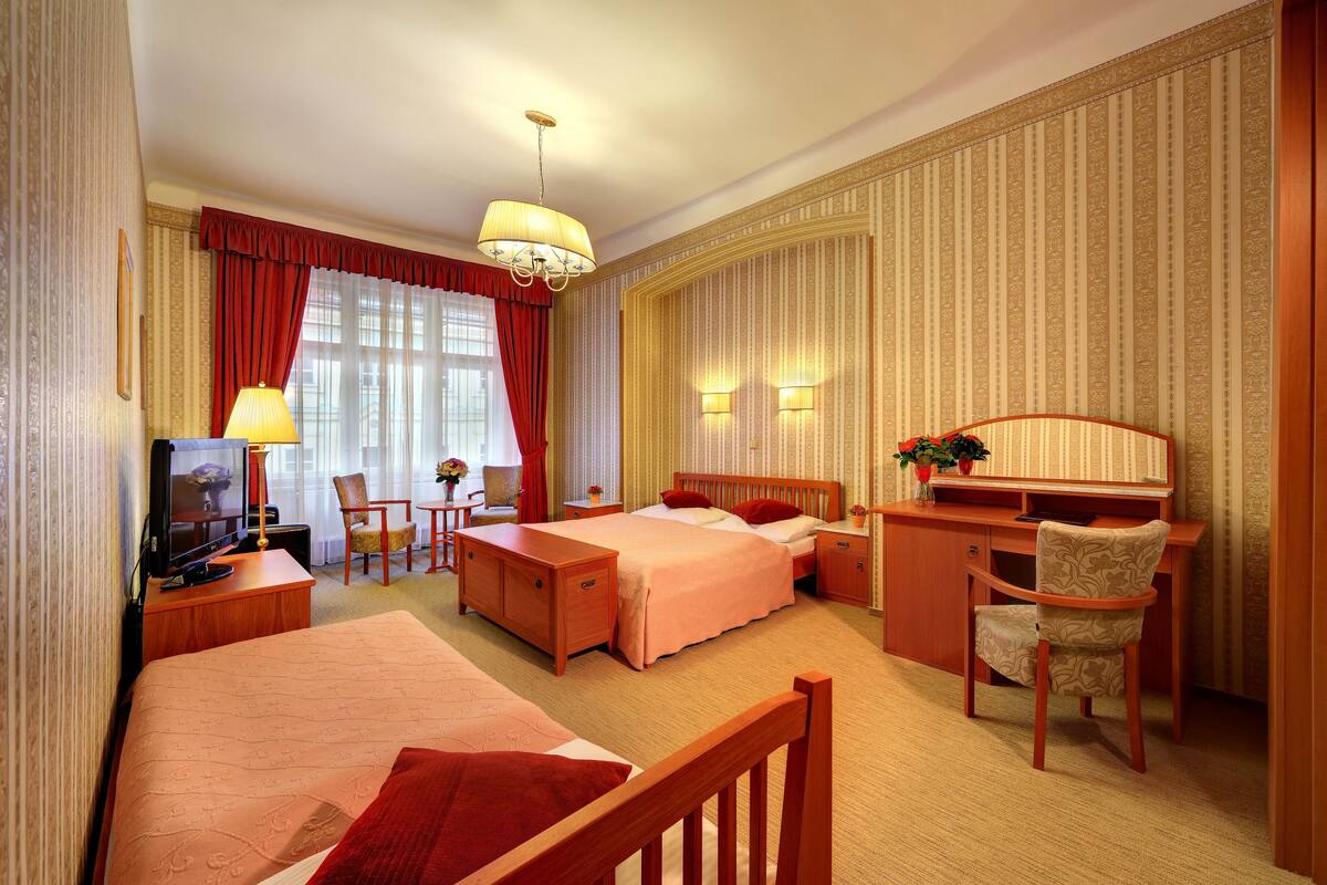 Een hotelkamer met twee bedden, een bureau, een stoel, een televisie en een lamp.