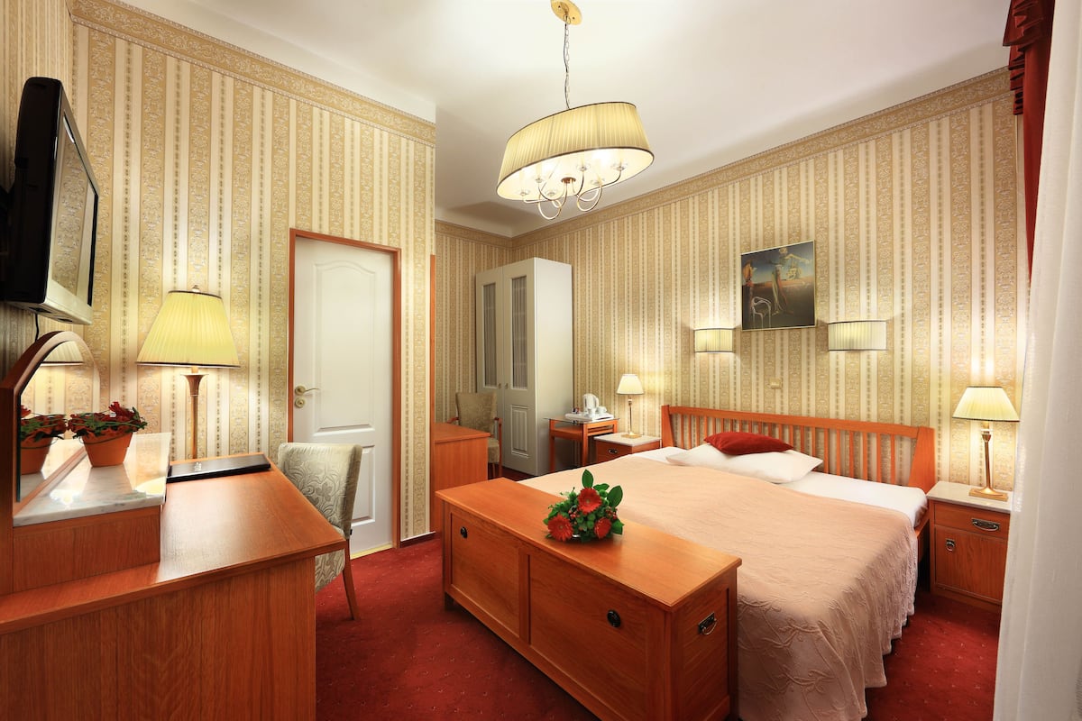 Een hotelkamer met een groot bed, een bureau, een stoel, een televisie en een spiegel.