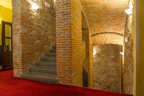 A staircase with stone walls and a red carpeted floor.