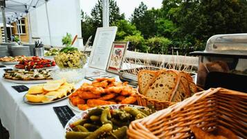 A buffet table with various food items and a menu sign.