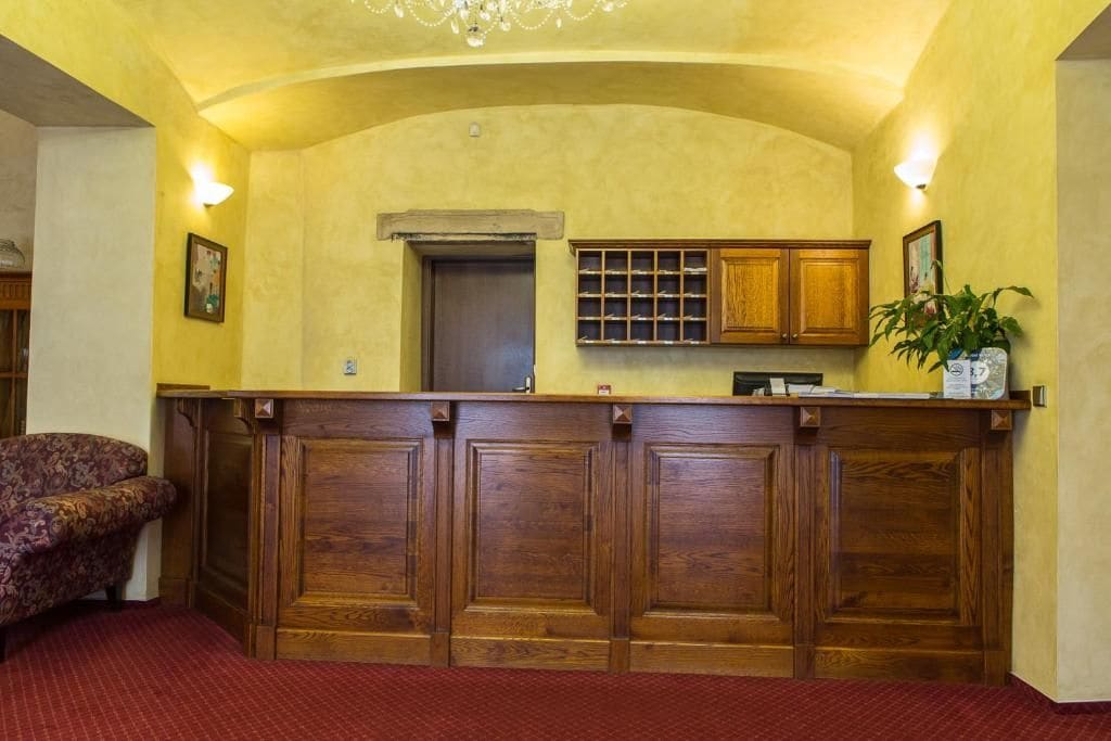 A reception area with a wooden counter, a reception desk, a potted plant, and a patterned sofa.