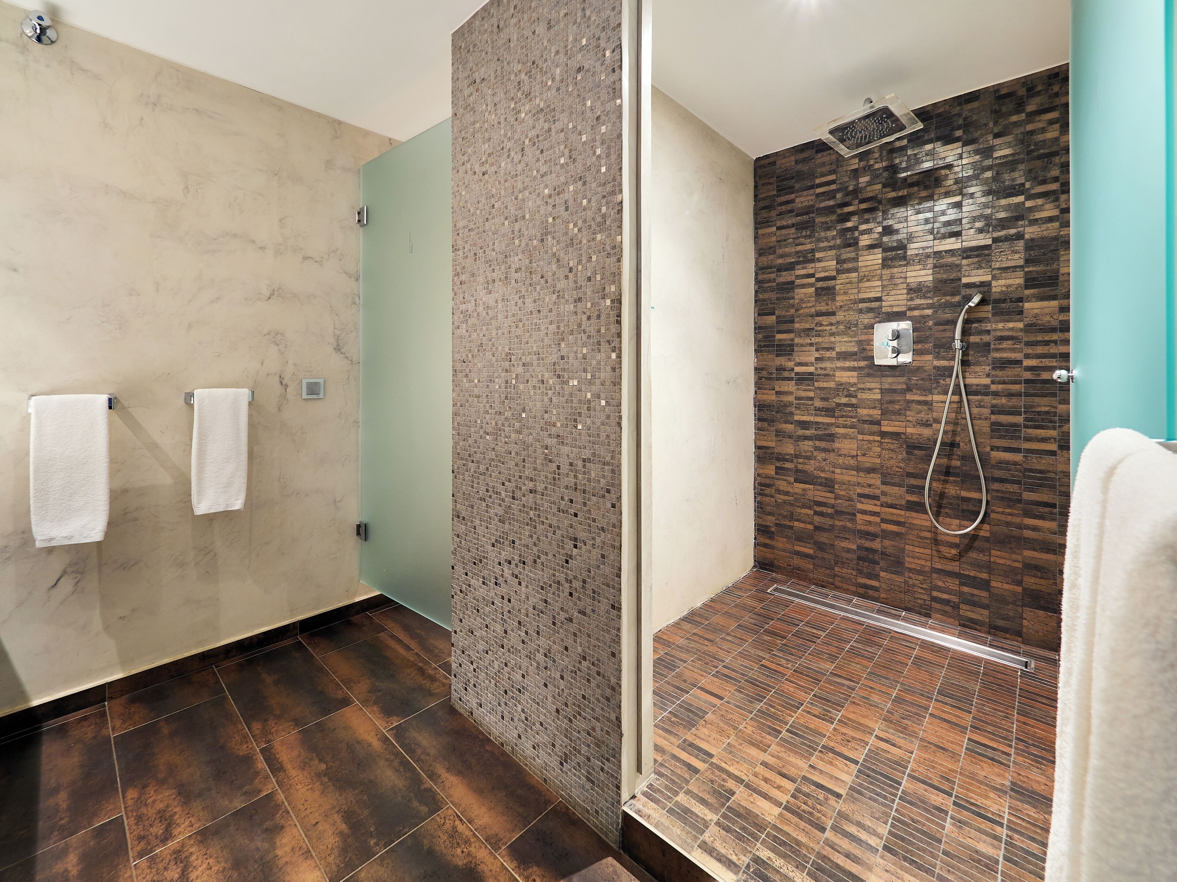 Un baño moderno con ducha, paredes de azulejos y suelo de mármol.