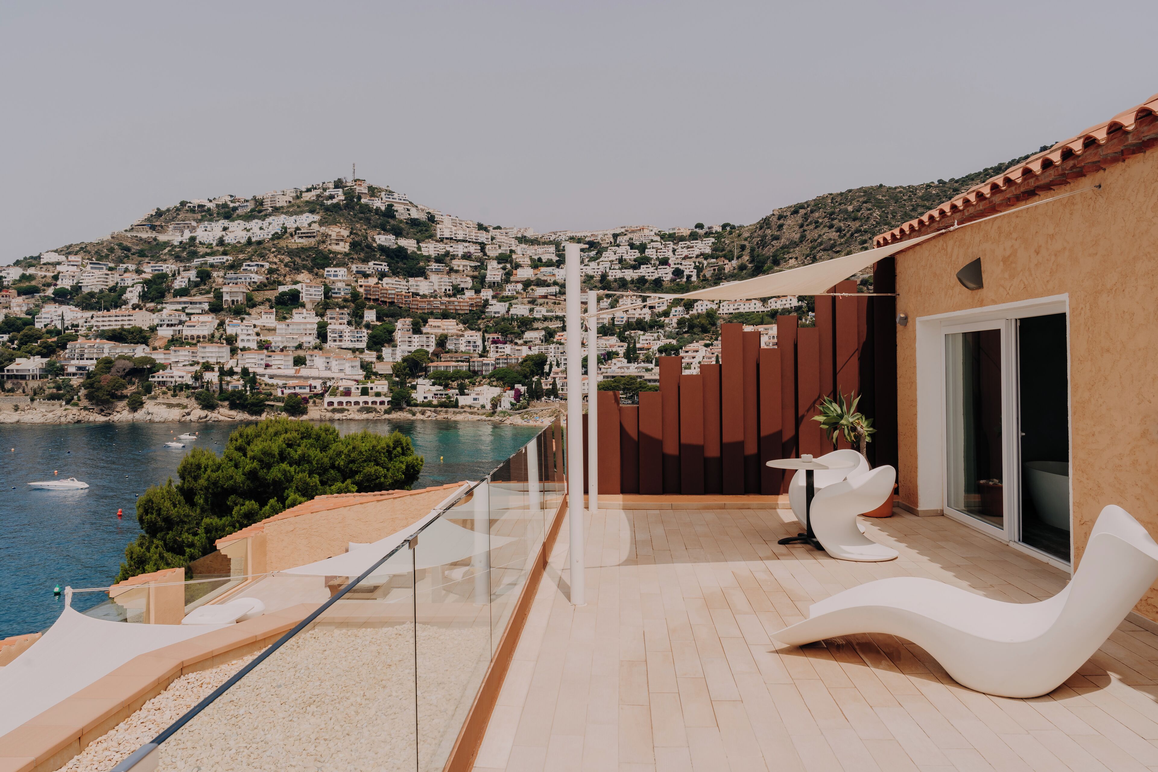 Une terrasse extérieure moderne offrant une vue sur une ville située sur une colline et sur un plan d’eau.