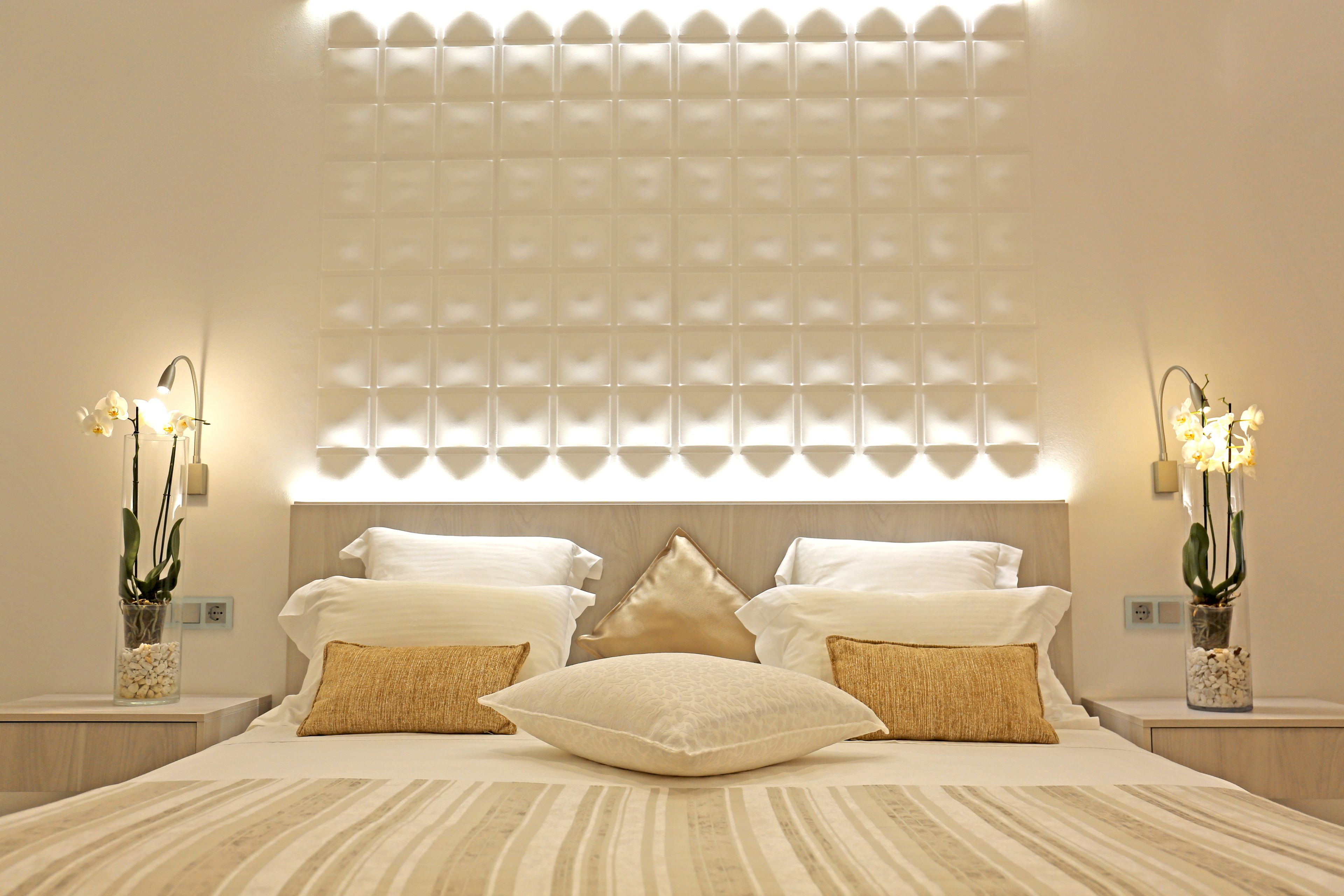 A modern bedroom with a large bed, two nightstands, and a wall-mounted light fixture.