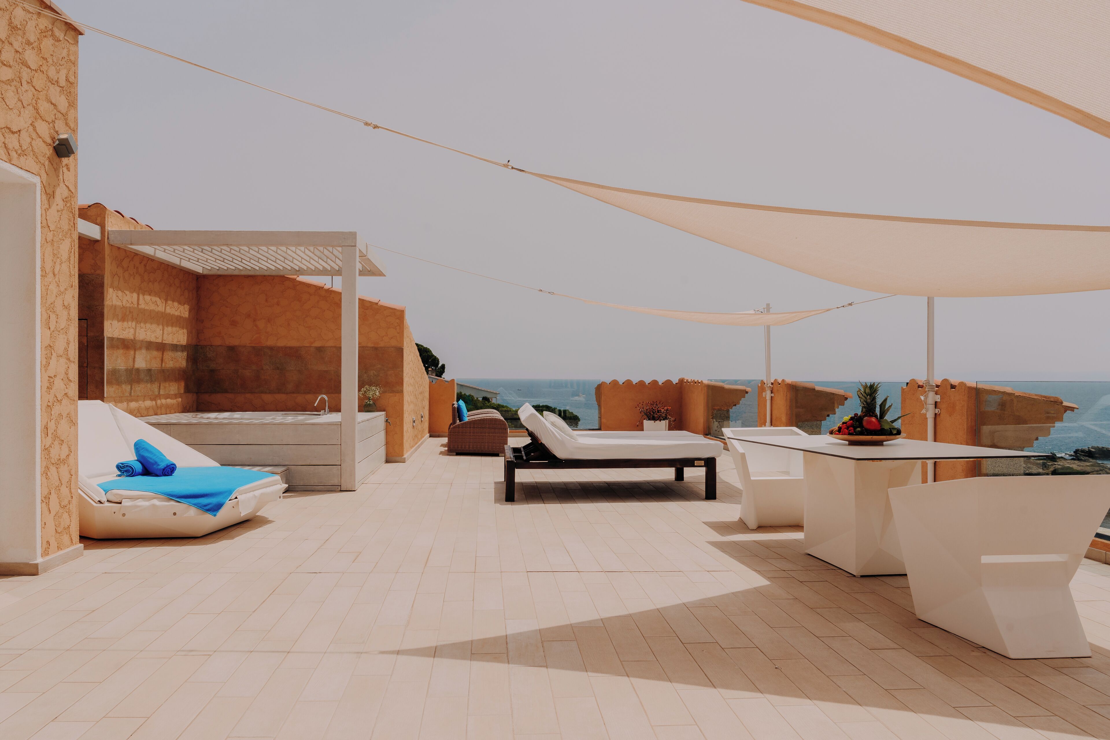 A rooftop terrace with a pool, lounge chairs, and a table with a fruit bowl.