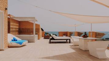 A rooftop terrace with a pool, lounge chairs, and a table with a fruit bowl.
