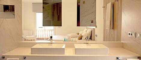 A modern bathroom with two sinks, a large mirror, and a towel rack.