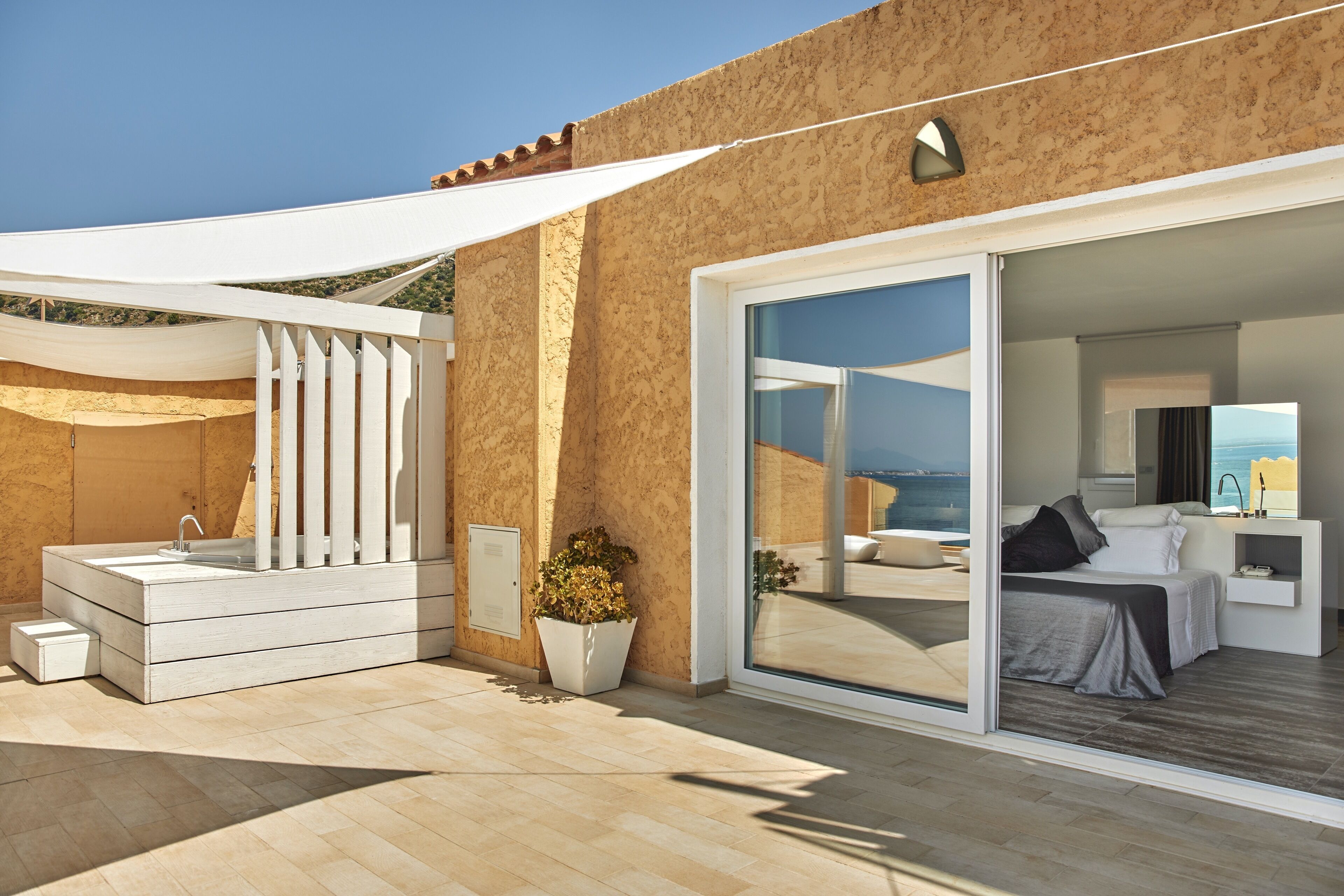A modern hotel room with a large sliding glass door leading to a balcony with a view of the sea.