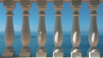 A balcony with white balustrades overlooking a clear blue sea.