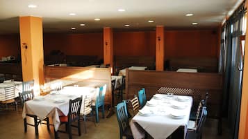 A restaurant with multiple tables and booths, each set with white tablecloths and plates.