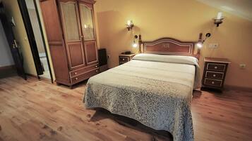 Een slaapkamer met een groot bed, een houten garderobe en bedlampjes.