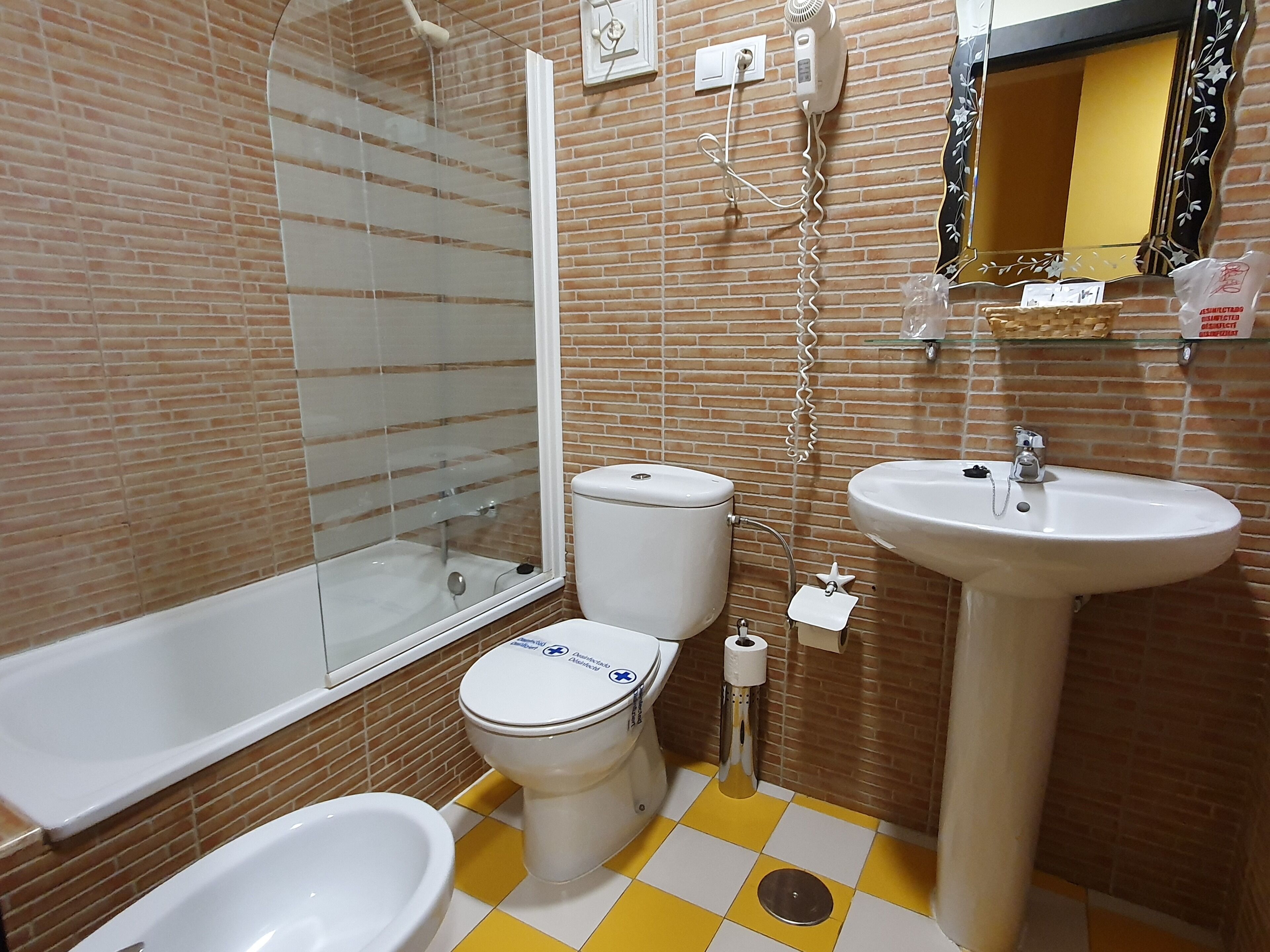 Un baño con inodoro, bidé, lavabo y zona de ducha.