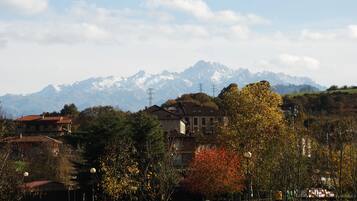 Paesaggio montuoso con edifici residenziali, un parco alberato e cielo sereno.