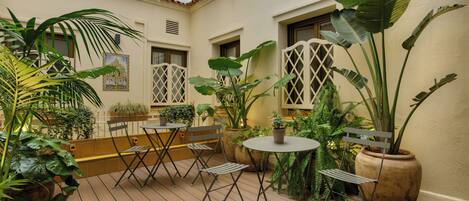 A courtyard with wooden flooring, potted plants, and outdoor furniture.