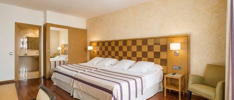 Habitación de hotel con una cama grande, un escritorio, una silla, un baño y un cabecero a cuadros.