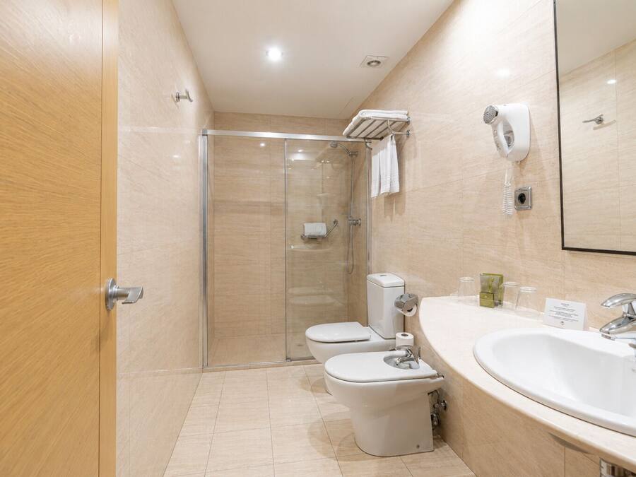 A modern bathroom with a glass-enclosed shower, a toilet, and a sink with a mirror.