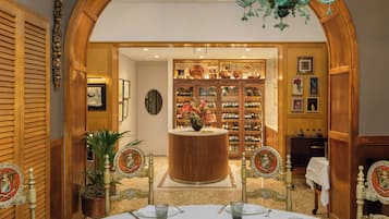 Zona pranzo con un tavolo rotondo apparecchiato per due, affiancata da eleganti sedie con schienali decorati.