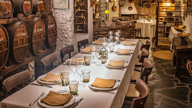 A restaurant with a long dining table set for a meal, surrounded by wooden barrels and rustic decor. - Duran Hotel & Restaurant (Figueres)