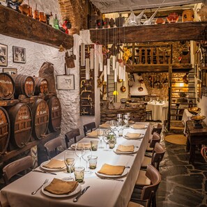 Un restaurante con una larga mesa de comedor dispuesta para una comida, rodeado de barriles de madera y decoración rústica.