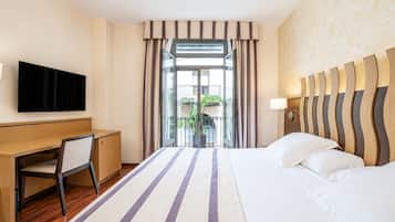 Een hotelkamer met een bed, bureau, televisie en uitzicht op de omgeving.