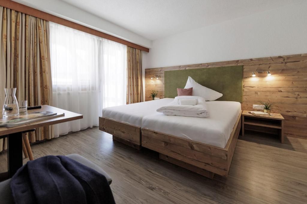 Ein Schlafzimmer mit einem Holzbettgestell, einem Schreibtisch mit Stuhl und einem Nachttisch mit Lampe.