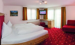 Ein Schlafzimmer mit einem hölzernen Bett, einem Schreibtisch, einem roten Sessel und einem Fernseher an der Wand.