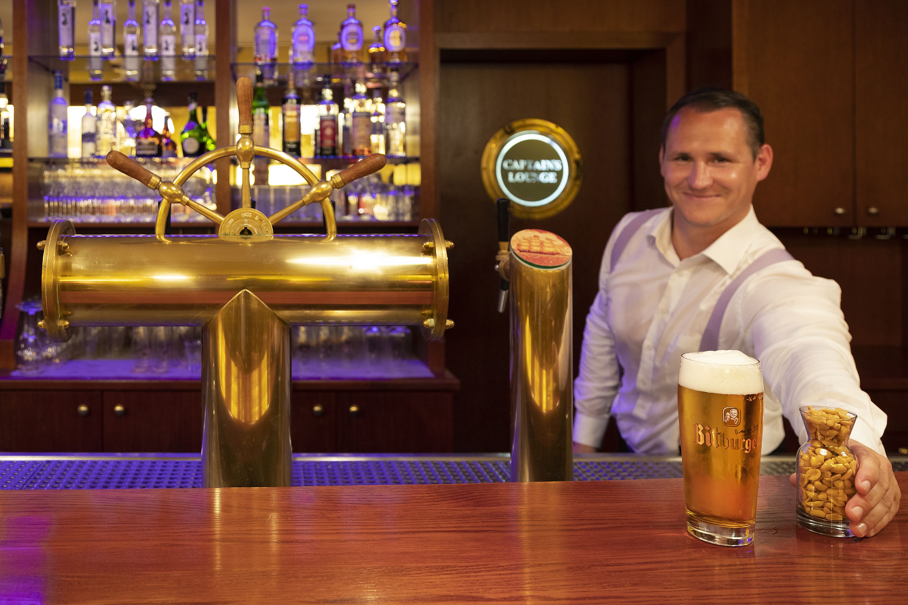 A bar with a brass beer tap and a glass of beer.