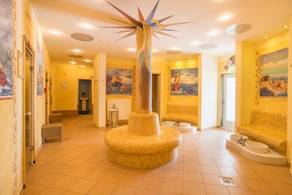 A hotel lobby with a central pillar, tiled floors, and artwork on the walls. - Hotel zur Post – ein Rovell Hotel (Heringsdorf)