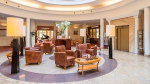 A spacious lobby with leather armchairs, a central table, and a piano. - Hotel zur Post – ein Rovell Hotel (Heringsdorf)