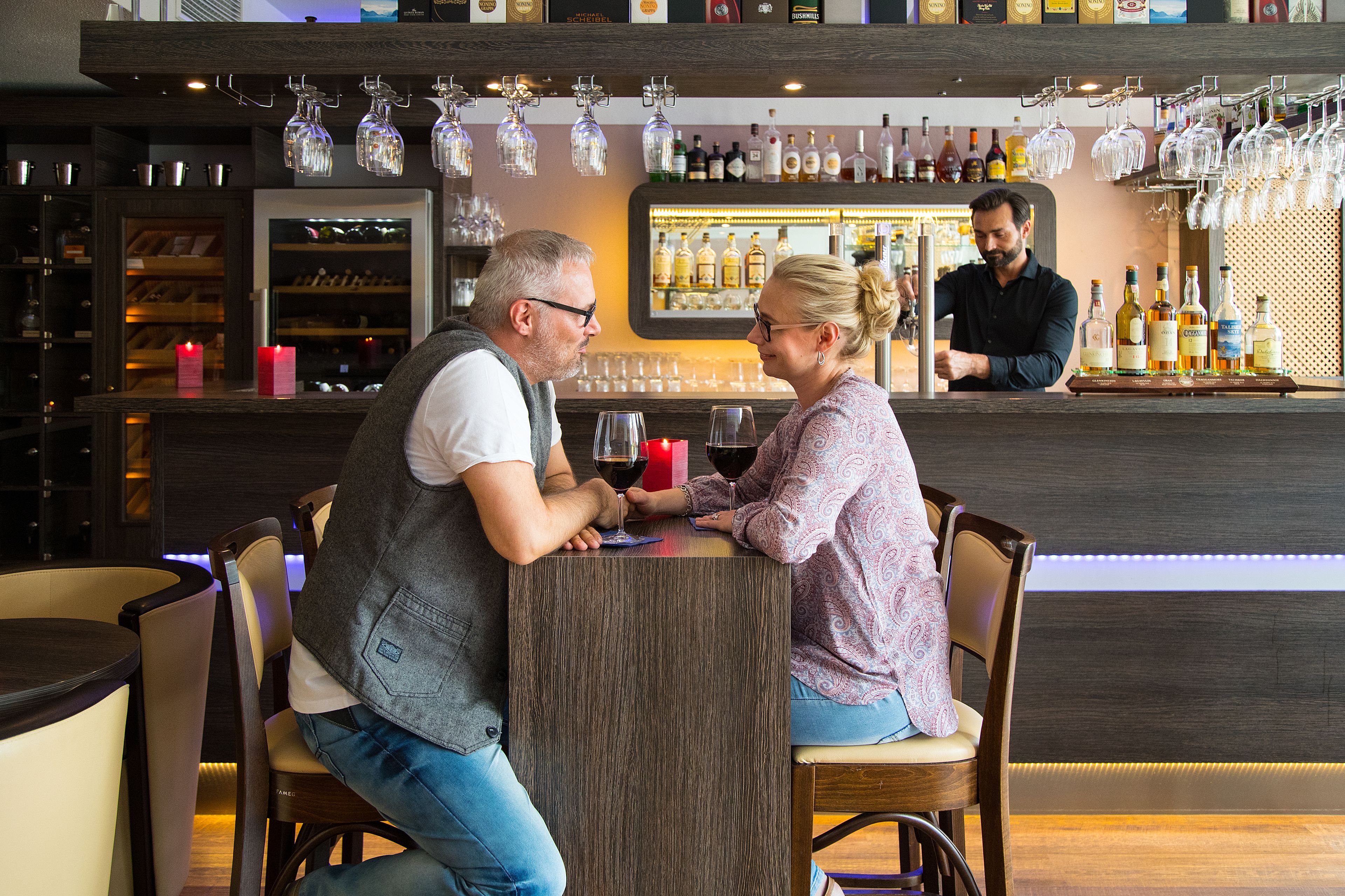 A bar area with a counter, wine glasses, and bottles.