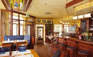 Interior de un restaurante con barra, muebles de madera y vistas al exterior.
