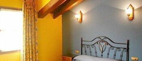 A bedroom with a bed, a wooden ceiling, a window with curtains, and wall-mounted lights.